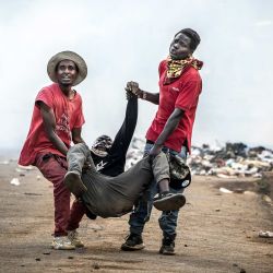 Manifestantes transportan a un manifestante gravemente herido en medio de gases lacrimógenos durante enfrentamientos con la policía keniana en una protesta contra un controvertido centro de cuarentena para el ébola construido por Estados Unidos en la base aérea de Laikipia, en Nanyuki. Varios kenianos fueron arrestados ese mismo día en las últimas protestas contra la construcción de un centro de cuarentena para ciudadanos estadounidenses en una ciudad turística. | Foto:LUIS TATO / AFP