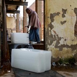 Un trabajador recoge bloques de hielo de una fábrica para entregarlos a los vendedores en un caluroso día de verano en Varanasi, India. | Foto:NIHARIKA KULKARNI / AFP