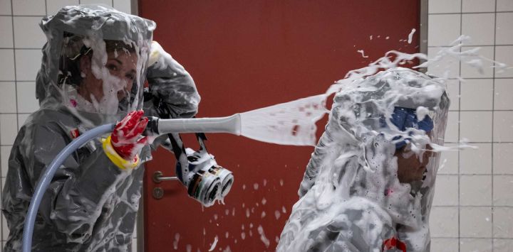 Dos enfermeras con sus EPI (Equipos de Protección Individual) utilizan un desinfectante espumoso en una cámara de descontaminación tras recibir a un paciente con una enfermedad altamente infecciosa como el ébola, durante una simulación en la sala de aislamiento especial del Departamento de Enfermedades Infecciosas del hospital Charité Virchow de Berlín. El hospital alemán dio de alta a un estadounidense que contrajo el ébola en la República Democrática del Congo, tras 17 días de tratamiento antiviral y atención médica que lo curaron de la infección, a menudo mortal.