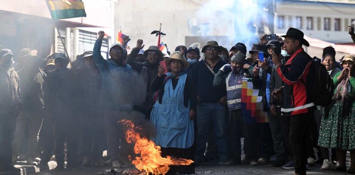 Manifestantes corean consignas cerca de un objeto en llamas durante una protesta contra el gobierno del presidente boliviano Rodrigo Paz en La Paz. Durante semanas, manifestantes que exigían que el incipiente gobierno del presidente conservador Rodrigo Paz, respaldado por Estados Unidos, abordara una profunda crisis económica, mientras que otros pedían su renuncia, marcharon y levantaron barricadas, paralizando prácticamente Bolivia, disparando los precios de los alimentos y el combustible y provocando escasez de productos básicos.