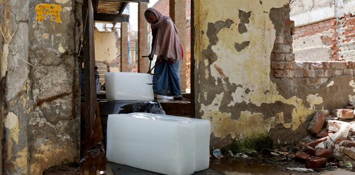Un trabajador recoge bloques de hielo de una fábrica para entregarlos a los vendedores en un caluroso día de verano en Varanasi, India.