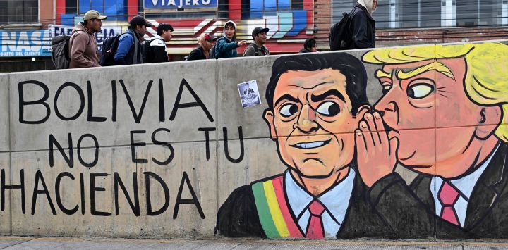 Jóvenes caminan junto a un muro con murales antigubernamentales durante un bloqueo vial en la zona de Río Seco, El Alto, Bolivia. Bolivia ha enfrentado días de protestas y bloqueos viales en medio de crecientes tensiones políticas y escasez de suministros que afectan a diferentes regiones del país.
