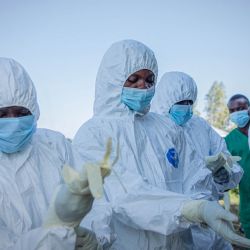 Voluntarios se colocan sus equipos de protección personal antes de recuperar el cuerpo de un niño de 3 años, presuntamente fallecido a causa del virus del Ébola, en Bunia, República Democrática del Congo. | Foto:Benediction Murhabazi / AFP