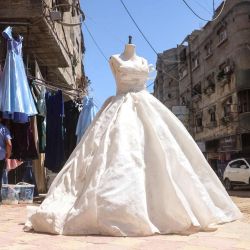 Una mujer palestina pasa junto a un taller de costura donde se confeccionan vestidos, incluyendo vestidos de noche y de novia, a pesar de los escasos recursos, y donde se reciclan vestidos viejos en la ciudad de Khan Yunis, en el sur de la Franja de Gaza. | Foto:Bashar Taleb / AFP