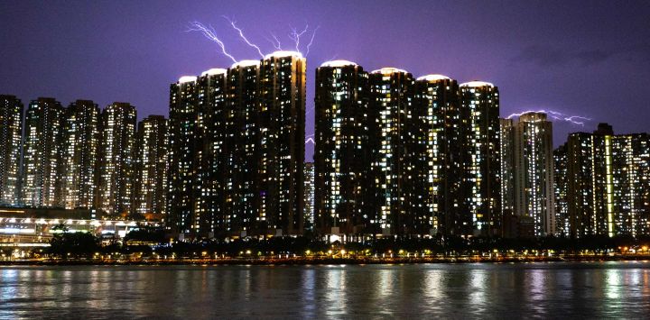Esta fotografía muestra relámpagos en el cielo detrás de un complejo residencial de gran altura en la isla de Tsing Yi, vistos desde el muelle de Tsuen Wan, en el distrito de Tsuen Wan de los Nuevos Territorios de Hong Kong.