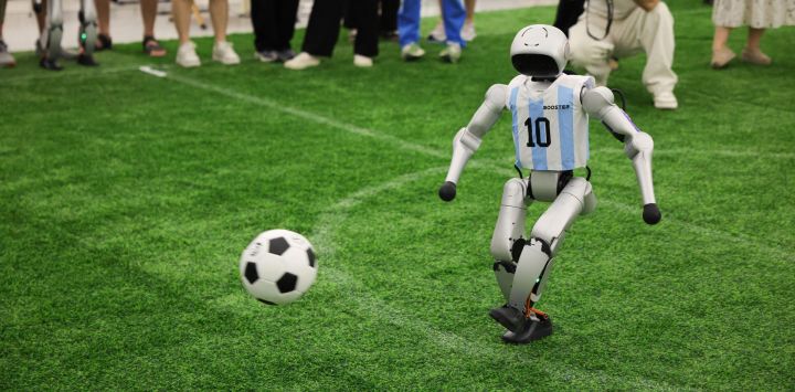 Imagen de un robot con la camiseta Selección Argentina jugando fútbol en el interior de un parque industrial de innovación en inteligencia encarnada, en Zhongguancun, distrito de Haidian de Beijing, capital de China. Este parque industrial alberga varias empresas destacadas en este campo. Gracias a la alta concentración de empresas, les resulta muy fácil encontrar socios a lo largo de la cadena de suministro, literalmente subiendo y bajando las escaleras del edificio de oficinas.