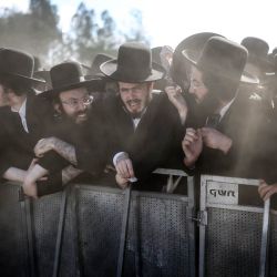 Judíos ultraortodoxos reaccionan tras una barrera durante una protesta contra el servicio militar obligatorio frente a la prisión militar de Bet Lid en Kfar Yona. Los legisladores israelíes votaron a favor de un proyecto de ley que permitiría a la mayoría de los hombres judíos ultraortodoxos evitar el servicio militar obligatorio, a pesar de las fuertes protestas de la oposición. Si bien los hombres ultraortodoxos han estado exentos del servicio militar en gran medida a lo largo de la historia moderna de Israel, el Tribunal Supremo ha cuestionado repetidamente esta situación en los últimos años, culminando en un fallo de 2024 que obliga al gobierno a reclutarlos. | Foto:ilia yefimovich / AFP