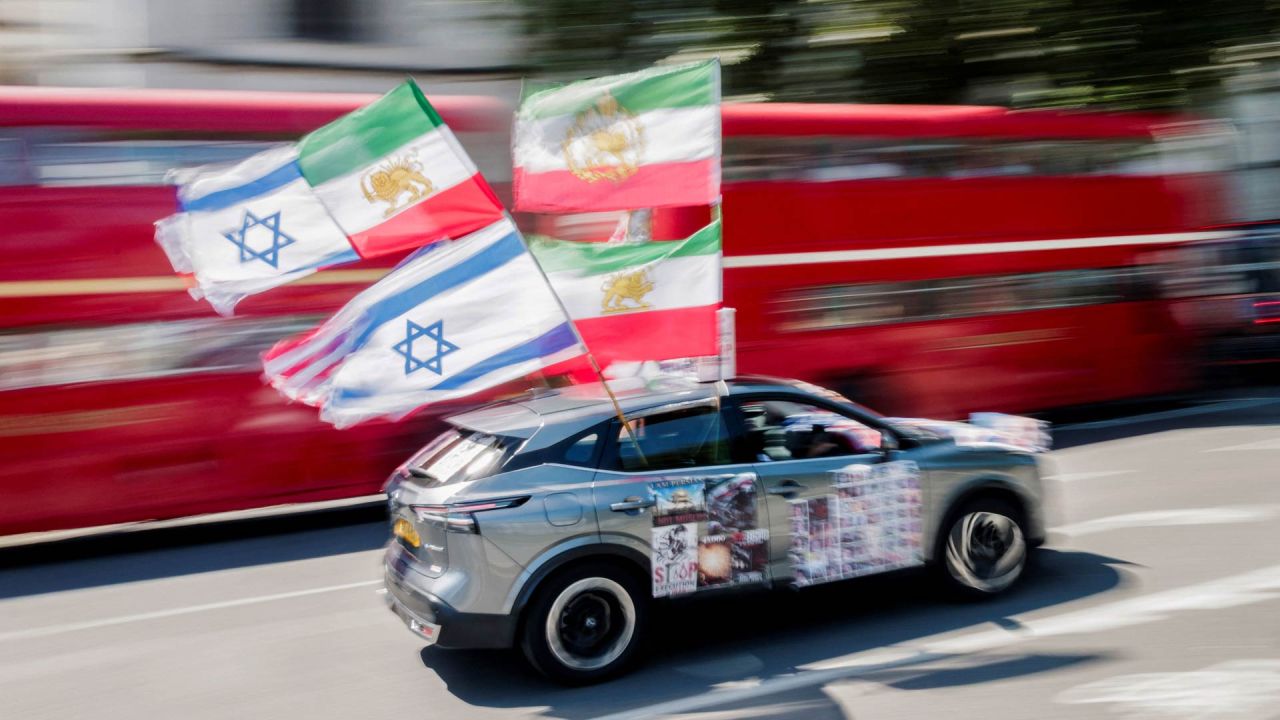 Un coche con banderas estadounidenses, israelíes y otras anteriores a la revolución de 1979 ondean al pasar junto a un grupo de manifestantes antirrégimen iraní reunidos frente al Parlamento en el centro de Londres, Inglaterra. | Foto:Brook Mitchell / AFP