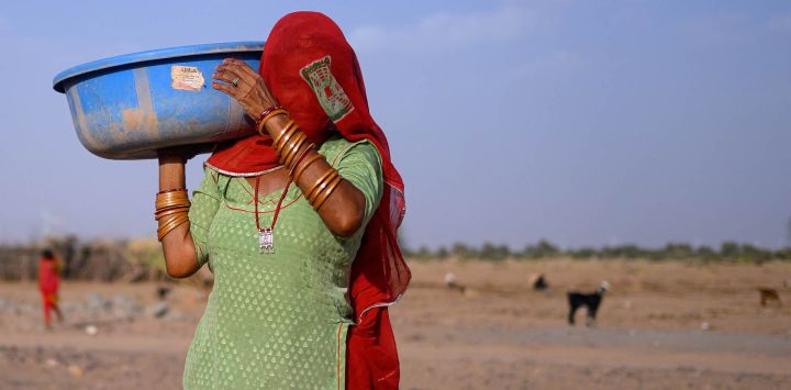 Esta muestra a Seema Kawar, madre del pastor Sawai Singh Bhati, cargando una bandeja de plástico tras alimentar al ganado frente a su casa en la aldea de Sanwata, en las afueras de Jaisalmer, Rajastán. En las calurosas llanuras de la India, los veranos abrasadores se han vuelto cada vez más difíciles de soportar, lo que exige adaptaciones y obliga a la vida a transcurrir en la oscuridad antes de que el sol se vuelva implacable. Las temperaturas en la aldea de Sanwata, donde vive Singh, alcanzaron los 45 °C a principios de junio, como suele ocurrir durante el verano, registrándose la temperatura máxima de 49 °C en la zona.