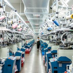 Imagen de un trabajador revisando calcetines frente a máquinas automáticas en un taller digital inteligente de una empresa, en la ciudad de Zhuji, en la provincia de Zhejiang, en el este de China. | Foto:Xinhua/Guo Bin