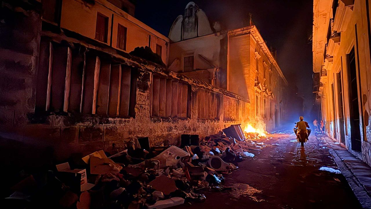 Un motociclista pasa junto a una pila de basura en llamas durante un apagón en La Habana, Cuba. | Foto:PABLO PORCIUNCULA / AFP