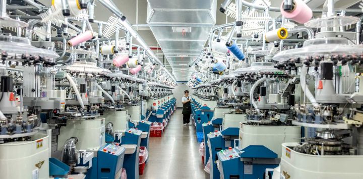 Imagen de un trabajador revisando calcetines frente a máquinas automáticas en un taller digital inteligente de una empresa, en la ciudad de Zhuji, en la provincia de Zhejiang, en el este de China.