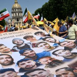 Manifestantes corean consignas mientras sostienen una pancarta gigante con los retratos de ciudadanos iraníes desaparecidos durante una manifestación no autorizada organizada por asociaciones franco-iraníes, entre ellas el Comité de Apoyo a los Derechos Humanos en Irán (CSDHI), y ONG francesas e internacionales en apoyo a la oposición iraní, cerca de la plaza Vauban, en el centro de París, Francia. | Foto:ARNAUD FINISTRE / AFP