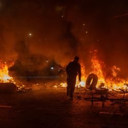 Un hombre arroja un neumático al fuego durante enfrentamientos con la policía mientras manifestantes protestan contra los resultados preliminares de la segunda vuelta de las elecciones presidenciales en Bogotá, Colombia. | Foto:Diego Cuevas / AFP