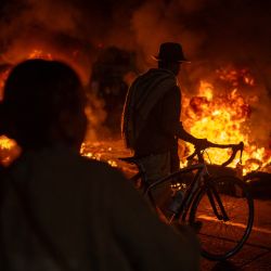 Un hombre camina con su bicicleta mientras manifestantes se encuentran frente a barricadas en llamas durante los enfrentamientos por los resultados preliminares de la segunda vuelta de las elecciones presidenciales en Bogotá, Colombia. | Foto:Diego Cuevas / AFP