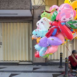 Un vendedor de globos se sienta frente a tiendas cerradas durante el Festival de la Moda de Surabaya en una calle de Surabaya, Indonesia. | Foto:JUNI KRISWANTO / AFP