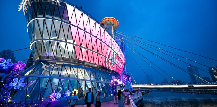 Imagen de personas visitando un complejo comercial y de ocio cerca del puente de Chifeng sobre el río Haihe, en Tianjin, en el norte de China. Renovado a partir de un antiguo edificio en desuso y reabierto al público en mayo, el complejo comercial y de ocio atrae a numerosos turistas durante el Festival del Bote del Dragón. En los últimos años, Tianjin ha aprovechado los recursos históricos y culturales a lo largo del río Haihe para impulsar la economía nocturna.