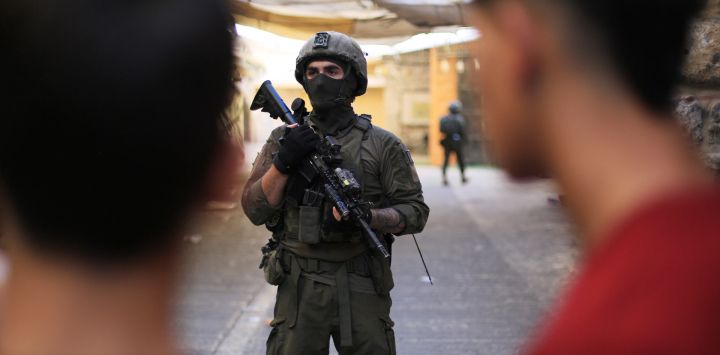 Imagen de un integrante de las fuerzas israelíes asegurando las calles para colonos israelíes, en la ciudad cisjordana de Hebrón.