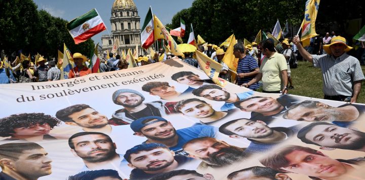 Manifestantes corean consignas mientras sostienen una pancarta gigante con los retratos de ciudadanos iraníes desaparecidos durante una manifestación no autorizada organizada por asociaciones franco-iraníes, entre ellas el Comité de Apoyo a los Derechos Humanos en Irán (CSDHI), y ONG francesas e internacionales en apoyo a la oposición iraní, cerca de la plaza Vauban, en el centro de París, Francia.