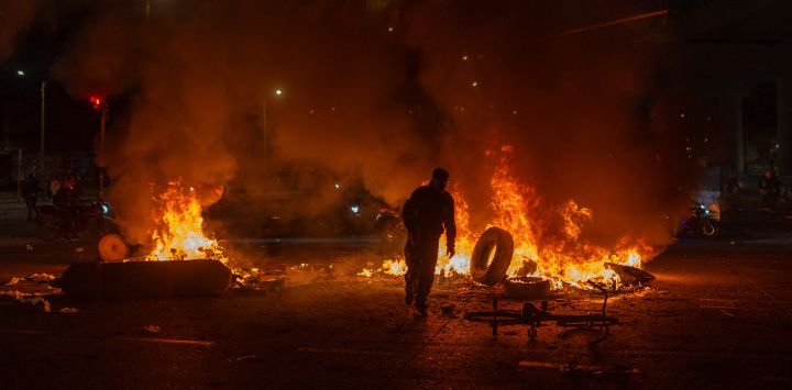 Un hombre arroja un neumático al fuego durante enfrentamientos con la policía mientras manifestantes protestan contra los resultados preliminares de la segunda vuelta de las elecciones presidenciales en Bogotá, Colombia.