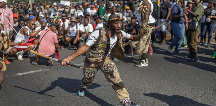 Un manifestante vestido con atuendo tradicional zulú hace un gesto durante una protesta de miembros del Movimiento «Marcha y Marcha» en el municipio de Umlazi, al suroeste de Durban, Sudáfrica.