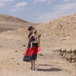 Una mujer israelí sostiene a su hijo cerca del antiguo yacimiento arqueológico de la "Piscina de Herodes", cerca del asentamiento judío de Petzael, en la Cisjordania palestina ocupada por Israel, en el Valle del Jordán, después de que el agua de un manantial cercano fuera desviada hacia el lugar. Las autoridades israelíes están investigando las obras no autorizadas y el desvío de agua por parte de colonos israelíes que, según informes, han tomado el control del yacimiento arqueológico y desviado agua de tierras de cultivo palestinas para llenar la antigua piscina. | Foto:ilia yefimovich / AFP