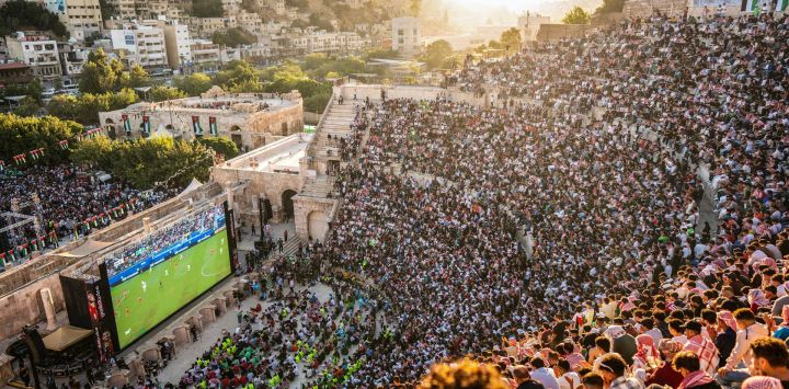 Aficionados jordanos se congregan para ver en pantallas gigantes el partido de fútbol de su selección nacional contra Argelia en el Grupo J del Mundial de 2026, en el anfiteatro romano del siglo II de Amán.
