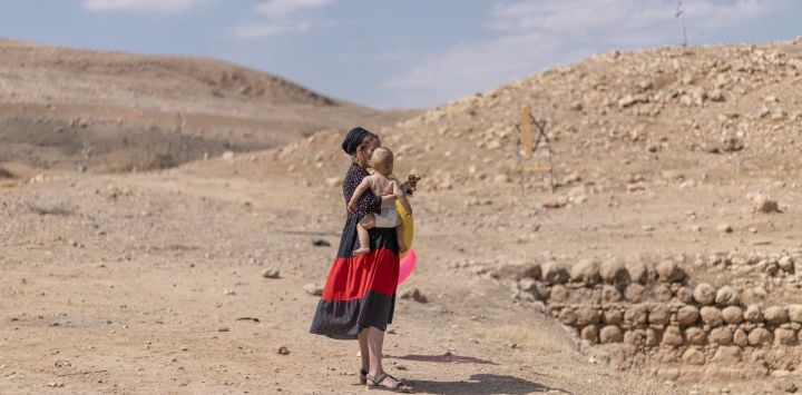 Una mujer israelí sostiene a su hijo cerca del antiguo yacimiento arqueológico de la "Piscina de Herodes", cerca del asentamiento judío de Petzael, en la Cisjordania palestina ocupada por Israel, en el Valle del Jordán, después de que el agua de un manantial cercano fuera desviada hacia el lugar. Las autoridades israelíes están investigando las obras no autorizadas y el desvío de agua por parte de colonos israelíes que, según informes, han tomado el control del yacimiento arqueológico y desviado agua de tierras de cultivo palestinas para llenar la antigua piscina.