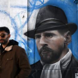 Un hombre camina cerca de un mural que representa al astro del fútbol argentino Lionel Messi en Buenos Aires. | Foto:LUIS ROBAYO / AFP