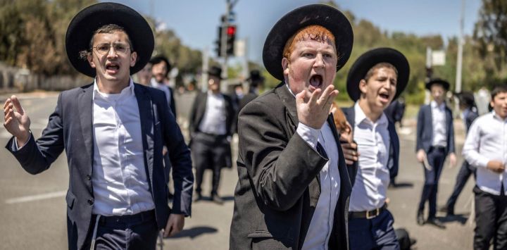 Judíos ultraortodoxos, en su mayoría exentos del servicio militar, protestan contra el reclutamiento obligatorio a la entrada de Tel Hashomer, el centro de reclutamiento del ejército israelí, en Ramat-Gan. El primer ministro de Israel, que depende de sus aliados del partido ultraortodoxo para mantenerse en el poder, ha empleado diversas tácticas para retrasar la aprobación de la legislación que permitiría el alistamiento de los judíos ultraortodoxos, quienes gozan de una amplia exención del servicio militar. Según una normativa establecida en la creación del país en 1948 —cuando la comunidad ultraortodoxa era pequeña—, los hombres que se dedican a tiempo completo al estudio de los textos sagrados judíos reciben una exención de facto.