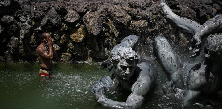 Un hombre se refresca en la fuente de los Girondinos en la Place des Quinconces, en medio de una ola de calor en Francia, en Burdeos, al suroeste del país.