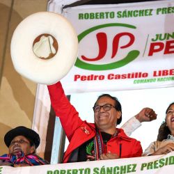 Roberto Sánchez, candidato presidencial del partido Juntos por el Perú, saluda a sus simpatizantes flanqueado por su primera candidata a la vicepresidencia, Anali Márquez (derecha), y su segunda candidata a la vicepresidencia, Brígida Curo, durante una marcha de protesta en Lima. Sánchez encabezó una marcha que exigía transparencia en el recuento de votos de la segunda vuelta, cuando se encontraba ligeramente por detrás de la candidata de derecha Keiko Fujimori. | Foto:CONNIE FRANCE / AFP
