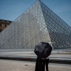 Una pareja se protege del sol bajo una sombrilla frente a la Pirámide del Louvre, diseñada por el arquitecto chino-estadounidense Ieoh Ming Pei, en París, durante una ola de calor en Francia. | Foto:DIMITAR DILKOFF / AFP