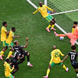 El defensor canadiense Moise Bombito, cabecea la pelota y falla una ocasión que logra detener el defensor sudafricano Aubrey Modiba, durante el partido de dieciseisavos de final del Mundial de 2026 entre Sudáfrica y Canadá, disputado en el Estadio de Los Ángeles en Inglewood. | Foto:Frederic J. Brown / AFP