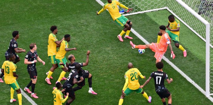 El defensor canadiense Moise Bombito, cabecea la pelota y falla una ocasión que logra detener el defensor sudafricano Aubrey Modiba, durante el partido de dieciseisavos de final del Mundial de 2026 entre Sudáfrica y Canadá, disputado en el Estadio de Los Ángeles en Inglewood.