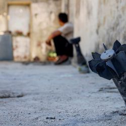 Un hombre conversa con un niño sentado cerca de un proyectil de artillería sin explotar que cayó durante el bombardeo israelí nocturno que impactó la aldea de Abidin, en la provincia de Daraa, al suroeste de Siria, cerca de los Altos del Golán. El Ministerio de Asuntos Exteriores de Siria condenó las incursiones y los bombardeos israelíes en el sur del país, un día después de que una escalada de violencia en la aldea, en la provincia de Daraa, obligara a sus residentes a huir temporalmente, según informaron funcionarios locales. | Foto:SAM HARIRI / AFP