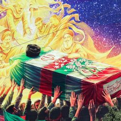 Un mural expuesto en la fachada de un edificio representa a figuras fallecidas alineadas con el gobierno iraní, como el difunto presidente Ebrahim Raisi, el difunto comandante de la Guardia Revolucionaria Islámica Qasem Soleimani, el difunto líder libanés de Hezbolá Hassan Nasrallah y otros, todos portando el ataúd cubierto con la bandera del difunto líder supremo de Irán, Ali Khamenei, quien murió en un ataque el primer día de la guerra entre Estados Unidos e Israel contra Irán, en la plaza Vanak de Teherán. | Foto:AFP