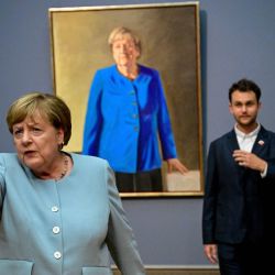 La excanciller alemana Angela Merkel le pide a un periodista que tenga cuidado cerca de las estatuas mientras ella y el artista franco-alemán Jeremie Queyras se encuentran junto a su pintura «Retrato de la excanciller federal Angela Merkel» durante su inauguración en el Museo Bode de Berlín. | Foto:TOBIAS SCHWARZ / AFP
