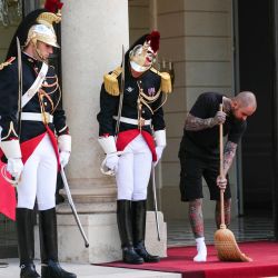 Un trabajador del Palacio del Elíseo barre junto a miembros de la Guardia Republicana antes de una reunión entre el presidente de Francia y el rey de Tailandia en el Palacio del Elíseo en París, Francia. | Foto:DIMITAR DILKOFF / AFP