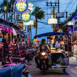 Un vendedor ambulante de comida pasa en moto junto a bares cerca de la playa de Pattaya, en Pattaya, Tailandia. | Foto:Anthony Wallace / AFP