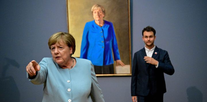 La excanciller alemana Angela Merkel le pide a un periodista que tenga cuidado cerca de las estatuas mientras ella y el artista franco-alemán Jeremie Queyras se encuentran junto a su pintura «Retrato de la excanciller federal Angela Merkel» durante su inauguración en el Museo Bode de Berlín.