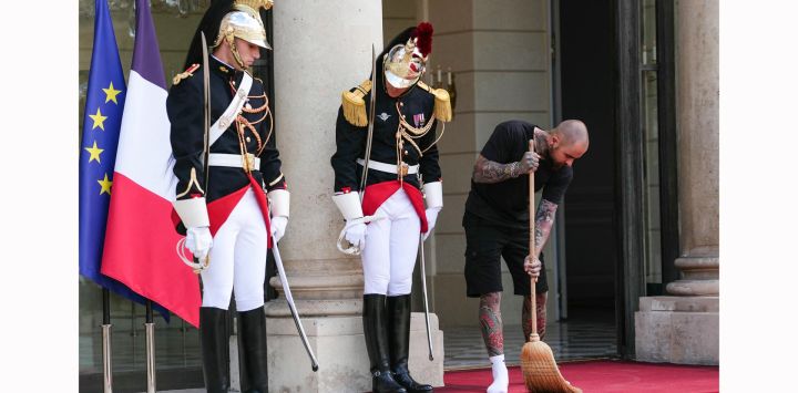 Un trabajador del Palacio del Elíseo barre junto a miembros de la Guardia Republicana antes de una reunión entre el presidente de Francia y el rey de Tailandia en el Palacio del Elíseo en París, Francia.