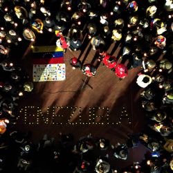 Esta vista aérea muestra a personas sosteniendo velas encendidas y una bandera venezolana durante una vigilia en homenaje a las víctimas de los terremotos en Venezuela. La palabra "VENEZUELA" se formó con velas en el suelo de la Plaza Estado del Vaticano en Buenos Aires. | Foto:LUIS ROBAYO / AFP