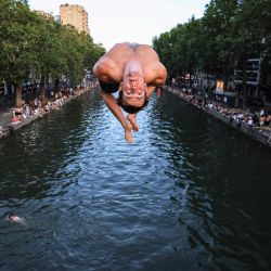 Un joven salta desde un puente al Canal Saint-Martin en medio de la ola de calor que azota Francia, en París. Debido a la ola de calor que afecta a Francia, un tramo del Canal Saint-Martin, en la capital francesa, se ha habilitado para el baño. | Foto:Ludovic Marin / AFP