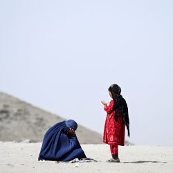 Una mujer afgana vestida con burka, acompañada de una niña, pide limosna en una carretera del distrito de Argo, en la provincia afgana de Badakhshan. | Foto:OMER ABRAR / AFP
