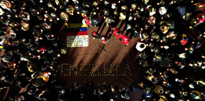 Esta vista aérea muestra a personas sosteniendo velas encendidas y una bandera venezolana durante una vigilia en homenaje a las víctimas de los terremotos en Venezuela. La palabra "VENEZUELA" se formó con velas en el suelo de la Plaza Estado del Vaticano en Buenos Aires.