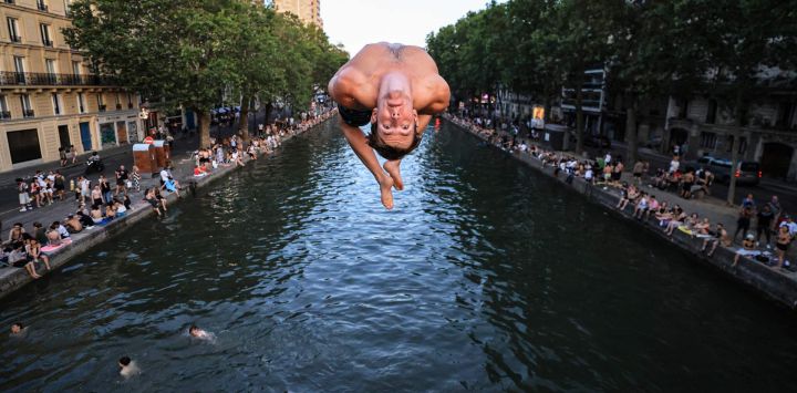 Un joven salta desde un puente al Canal Saint-Martin en medio de la ola de calor que azota Francia, en París. Debido a la ola de calor que afecta a Francia, un tramo del Canal Saint-Martin, en la capital francesa, se ha habilitado para el baño.