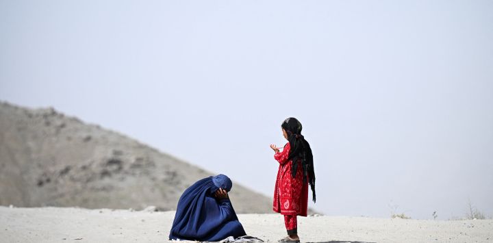 Una mujer afgana vestida con burka, acompañada de una niña, pide limosna en una carretera del distrito de Argo, en la provincia afgana de Badakhshan.