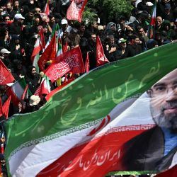 Los dolientes ondean una bandera con los retratos del actual líder supremo de Irán, Mojtaba Khamenei (izquierda), y su padre asesinado, Ali Khamenei, durante una procesión fúnebre en honor al líder supremo iraní asesinado, Ali Khamenei, y miembros de su familia en Teherán. | Foto:OZAN KOSE / AFP