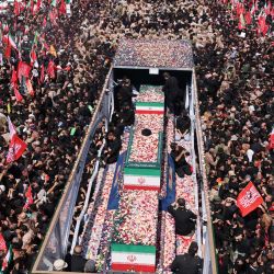 Pétalos de flores son arrojados sobre los ataúdes del asesinado líder supremo de Irán, Ali Khamenei, y sus familiares a lo largo de una calle durante su cortejo fúnebre en Teherán. | Foto:ATTA KENARE / AFP